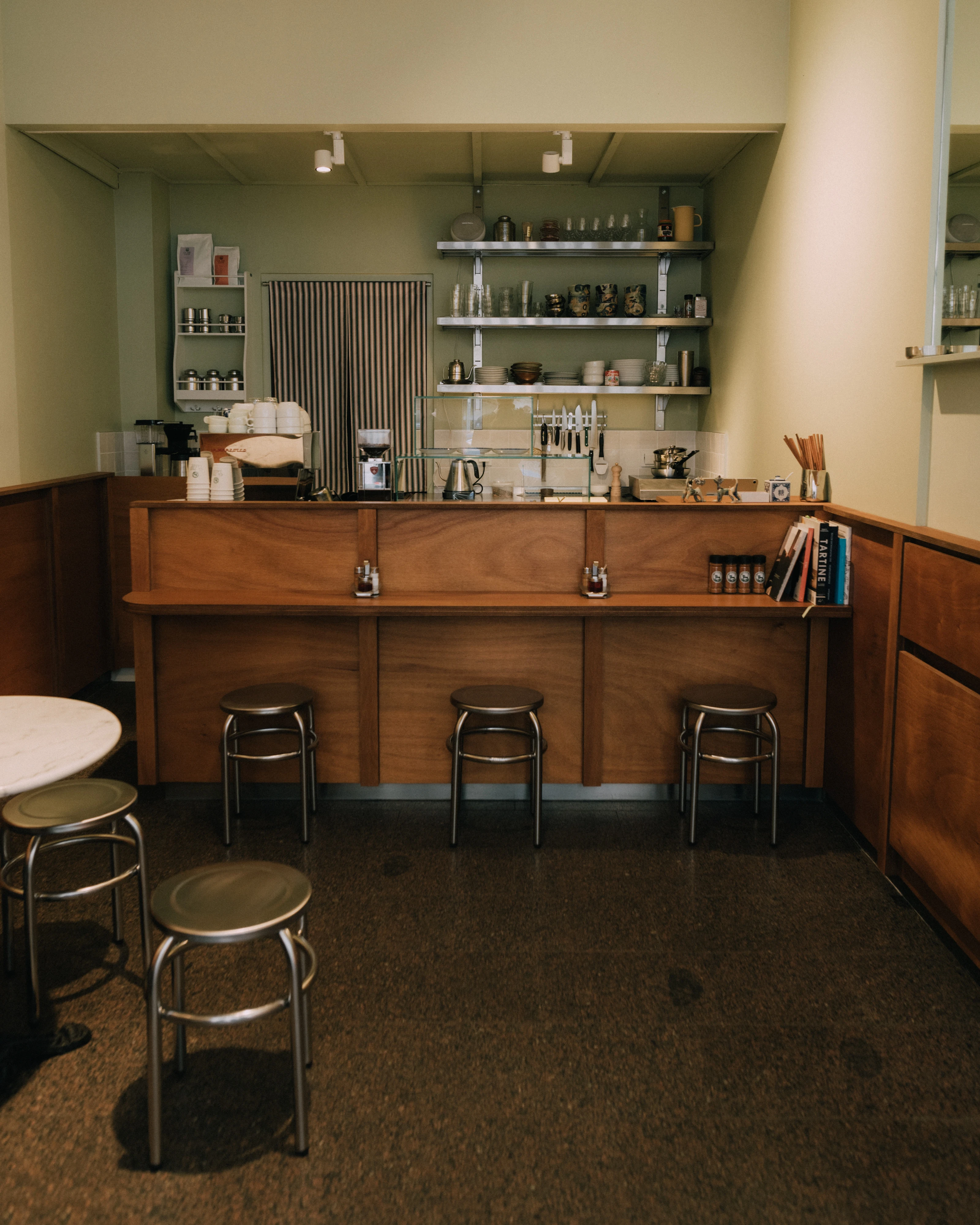 Café-Interieur mit Holztheke, Barhockern und Geschirr auf Regalen